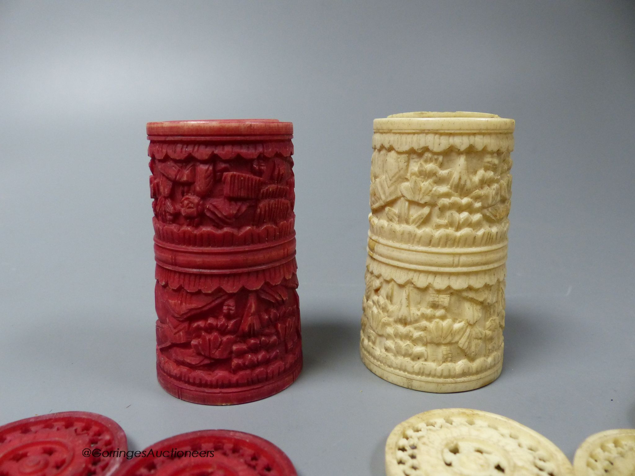 A Cantonese carved red stained and natural ivory draught set, including two shakers (18)